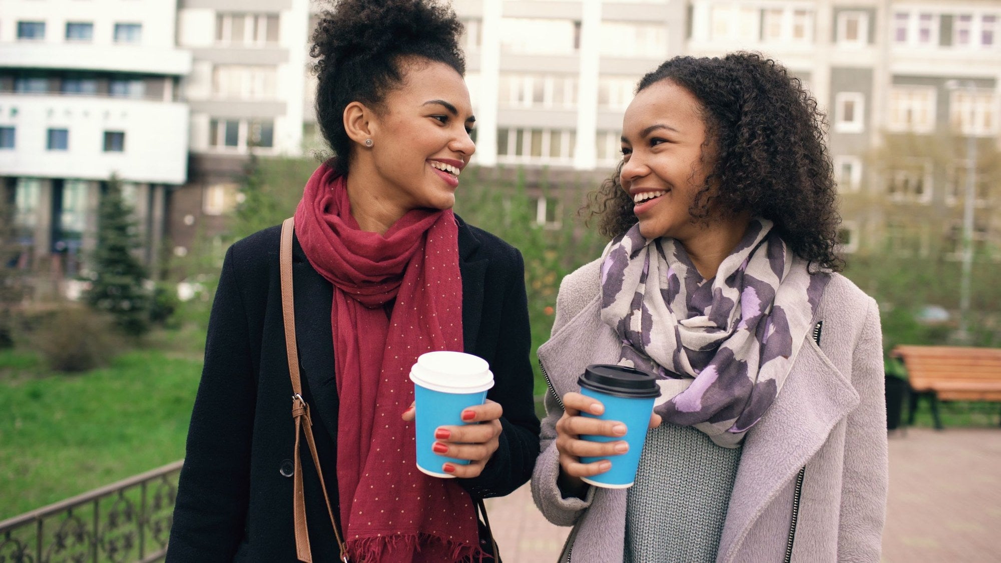 Dos amigas riéndose con un café en la calle